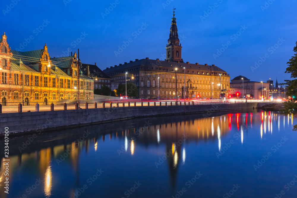 The Old Stock Exchange Boersen and Christiansborg Palace with their mirror reflection in canal at night, Copenhagen, capital of Denmark