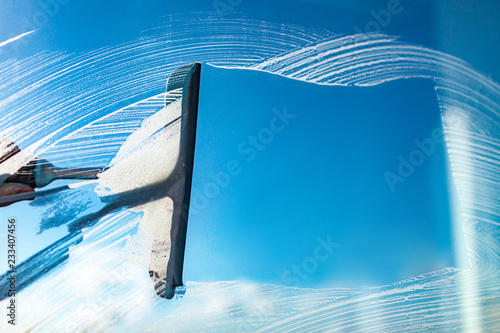 Cleaning windows with a squeegee on a blue sky background. Washing window photo