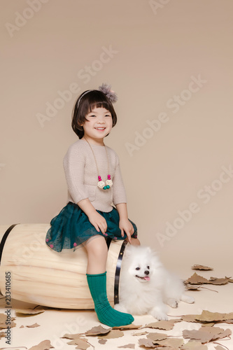 Little pretty Asian girl sitting in an autumn background.