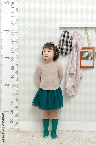 Little pretty Asian girl standing in a normal indoor life background.