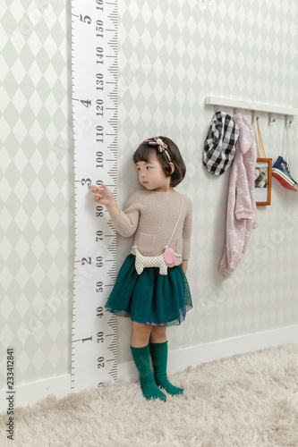 Little pretty Asian girl standing in a normal indoor life background.