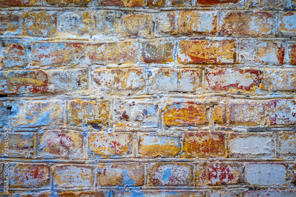 The texture of an old brick wall with traces of old paint of different colors_