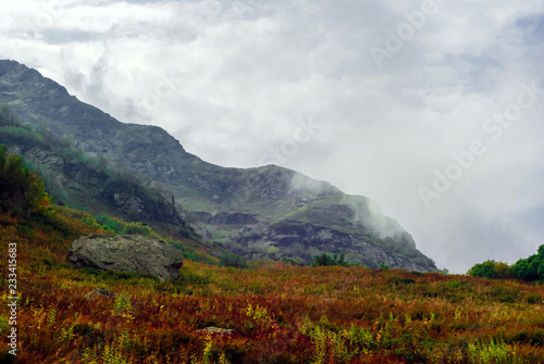 autumn mountain pass with red grass on the background of rainy mountains in the Caucasus