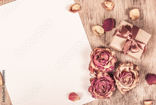 Blank paper, roses and gift. Suspended flowers, letter and gift box. Dried roses and clean paper
