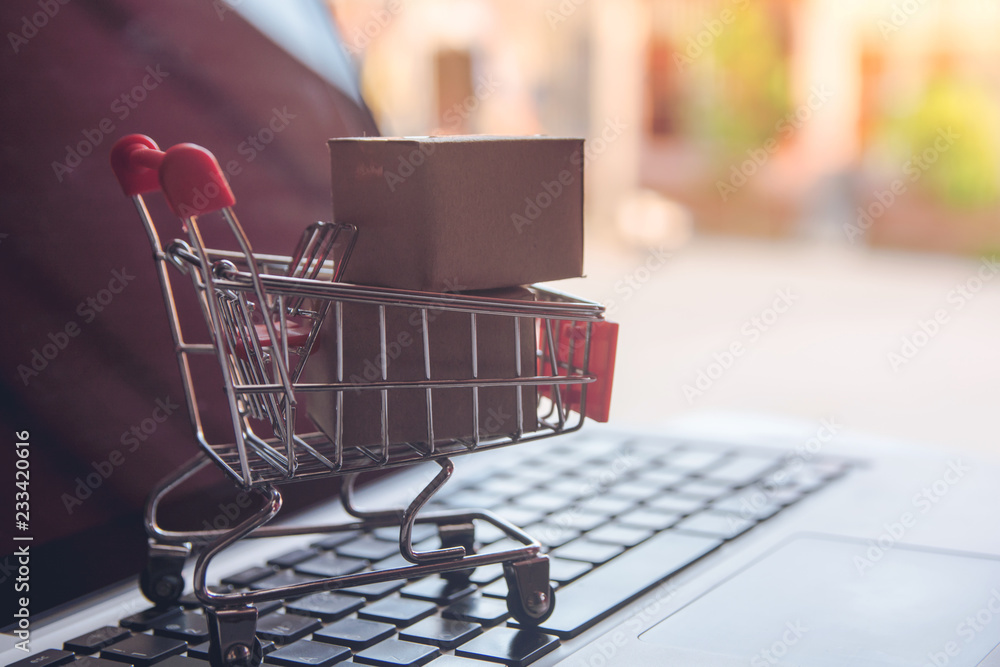 Shopping online concept - Shopping service on The online web. with payment by credit card and offers home delivery. parcel or Paper cartons with a shopping cart on a laptop keyboard