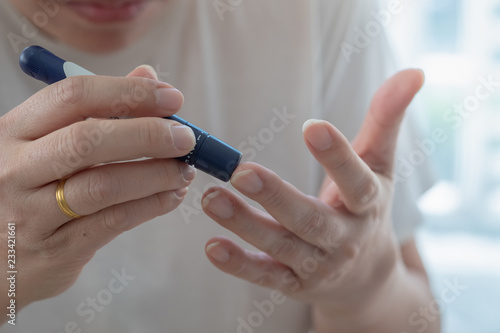 Close up of man hands using lancet on finger to check blood sugar level by Glucose meter using as Medicine  diabetes  glycemia  health care and people concept.