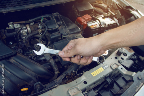 Car mechanic working with wrench in garage. Repair service.