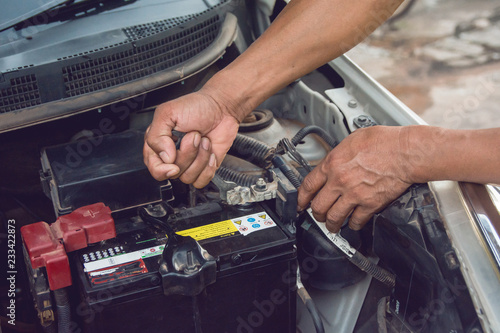 Car mechanic working Install battery with wrench in garage. Repair service.
