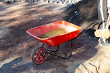 Red wheelbarrow with sand on construction site