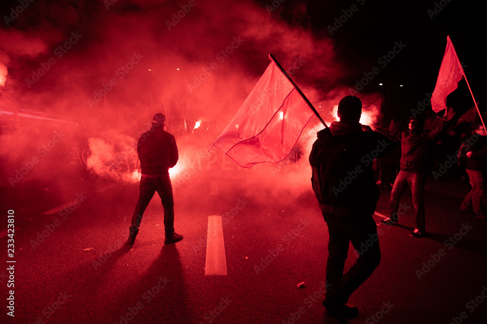 People carry Polish flags and burn flares as they walk across the Poniatowski Bridge during a march marking the 100th anniversary of Polish independence in Warsaw, Poland November 11, 2018.  - obrazy, fototapety, plakaty 