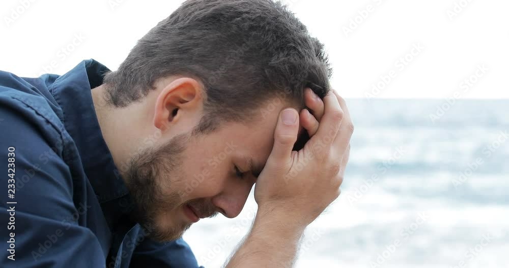 Portrait of a sad man crying on the beach
