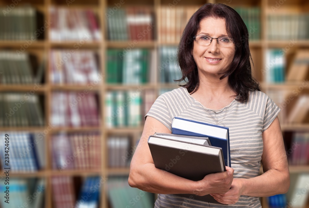 Mature woman teacher with books on background Mature woman teacher with books on background