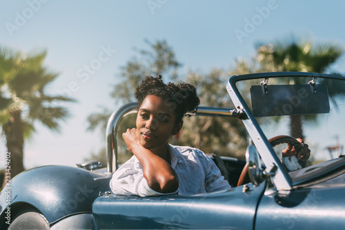Black woman driving a vintage convertible car © DavidPrado