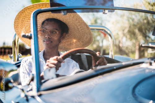 Black woman driving a vintage convertible car © DavidPrado