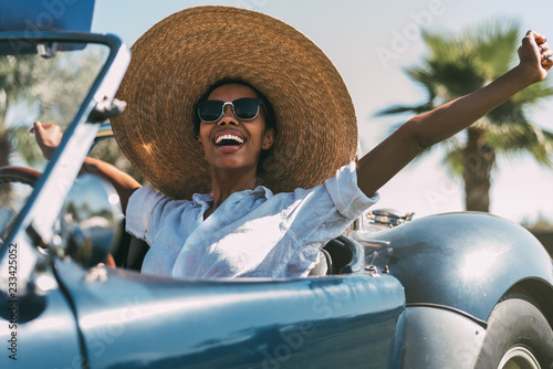 Black woman driving a vintage convertible car