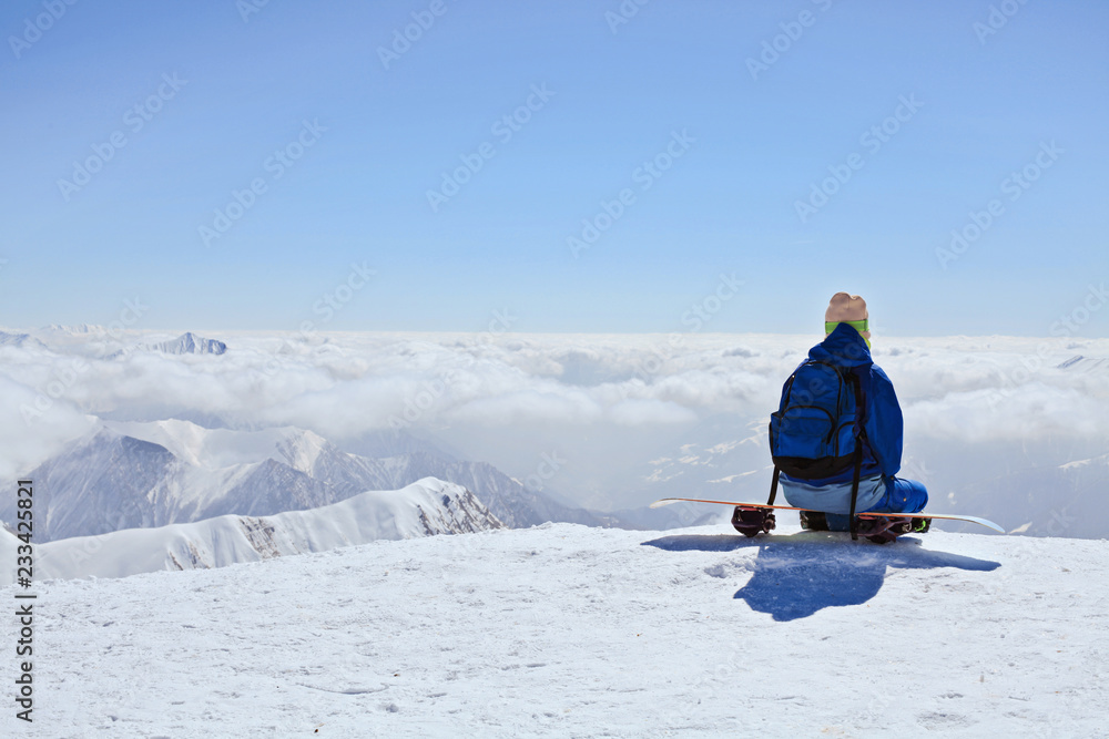 snow border sit on the top of the hill on his board  in nice sunny day. Caucasus Mountains in winter, Georgia, region Gudauri, Mount Kudebi.