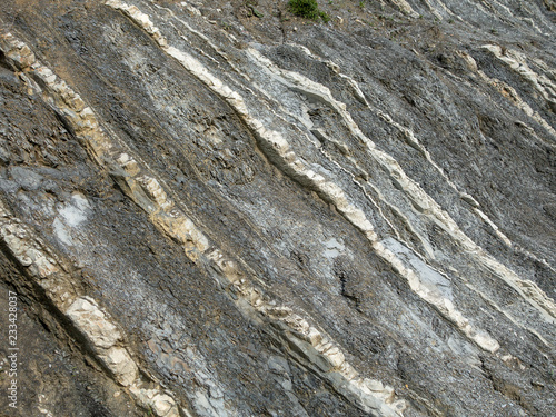 Mountain rock with gray, white and brown color stones diagonally arranged in strips. Background, macro, Caucasus