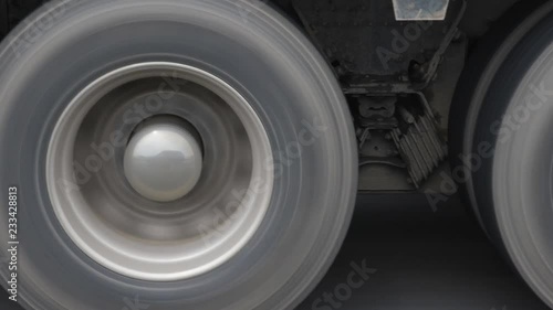 Closeup of truck wheels and tires with suspension. Passing truck on highway.