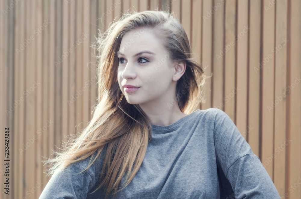 Portrait of a cute romantic girl on the background of the fence of brown boards. Youth culture. Fashion for young people. Energetic ambitious girl. Portrait of a cute romantic girl on the background of the fence of brown boards. Youth culture. Fashion for young people. Energetic ambitious girl.