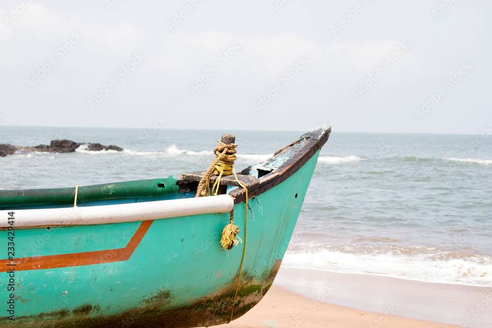 Old fishing boat standing on the sandy beach. India, Goa