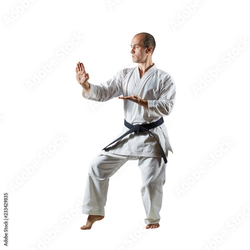 Athlete performs formal karate exercises on a white isolated background