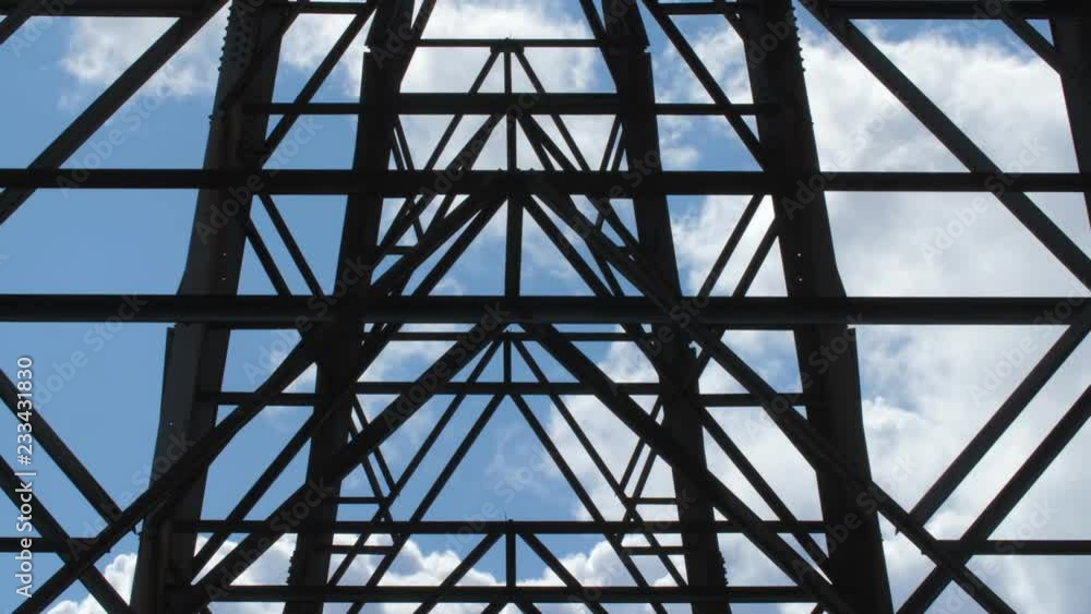 Detail of electrical pylon with clouds moving behind steel girders. Detail of electrical pylon with clouds moving behind steel girders.