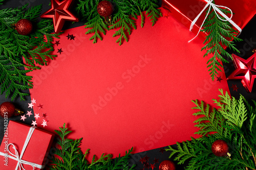 Christmas frame of red gift boxes  fir branches  confetti  paper for text and toys on black background. Flat lay. Top view. Copy space