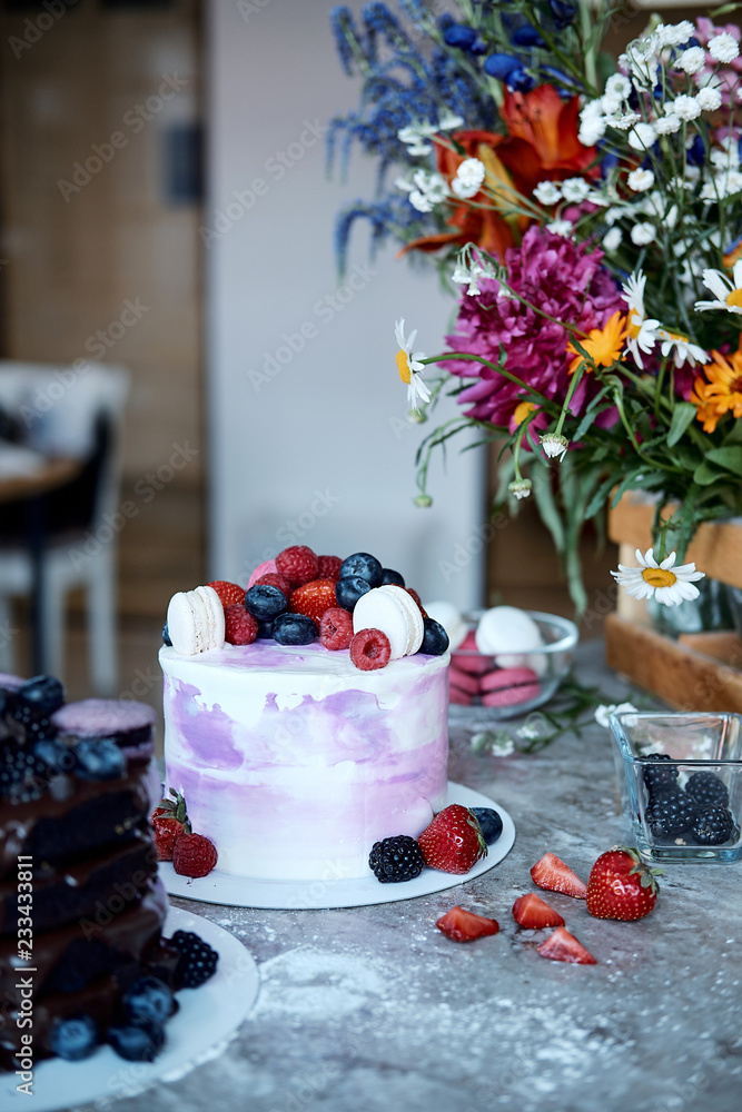 Holiday cake. Sweet desserts with berries and macarons. Cake from the fruit. Delicious sponge cake