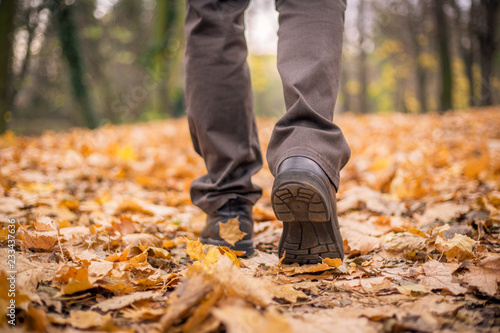 Feet shoes walking on fall leaves outdoor with autumn season nature  color toned image 