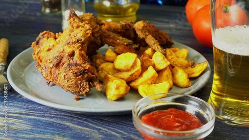 Crispy fried chicken wings with fried wedges on a plate. Breaded crispy chicken with baked potatoes for tasty dinner