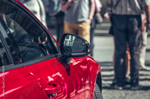 Selective and soft focus of side mirror and blurry red car on road with traffic jam.