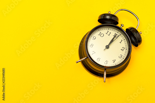 Black alarm clock with yellow background.