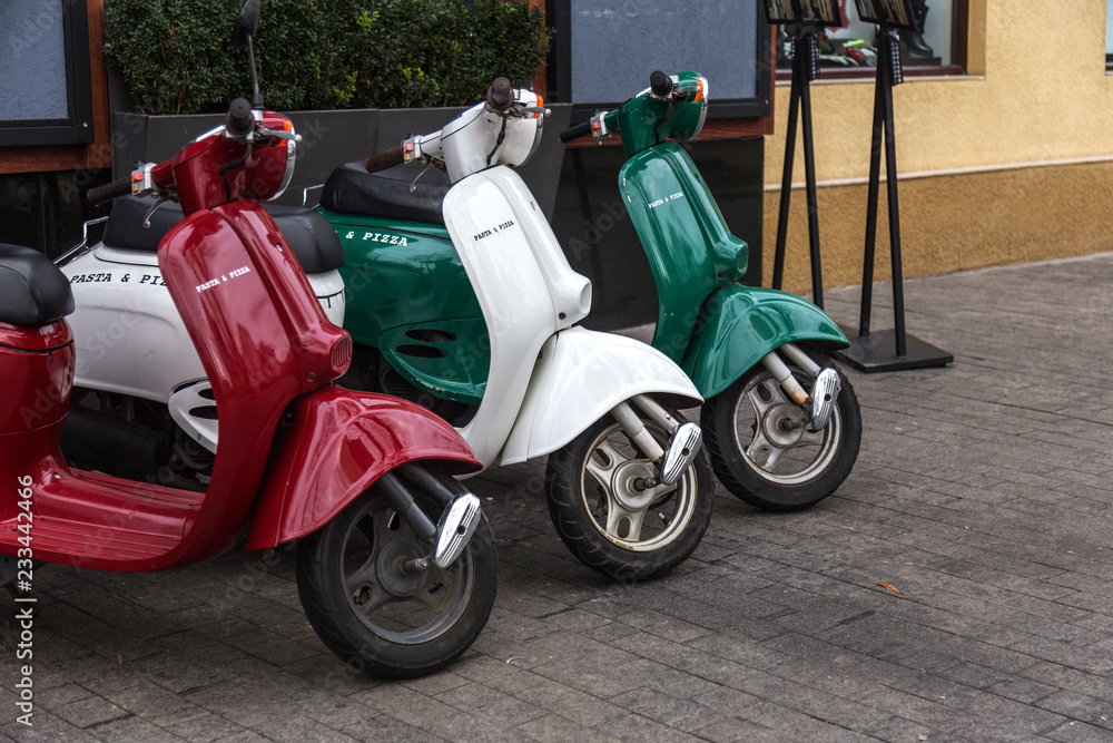 Motorcycles for pizza delivery, parked on the street, waiting for the order and delivery to the client. Mobile fast delivery of fresh hot pizza in the business part of the city