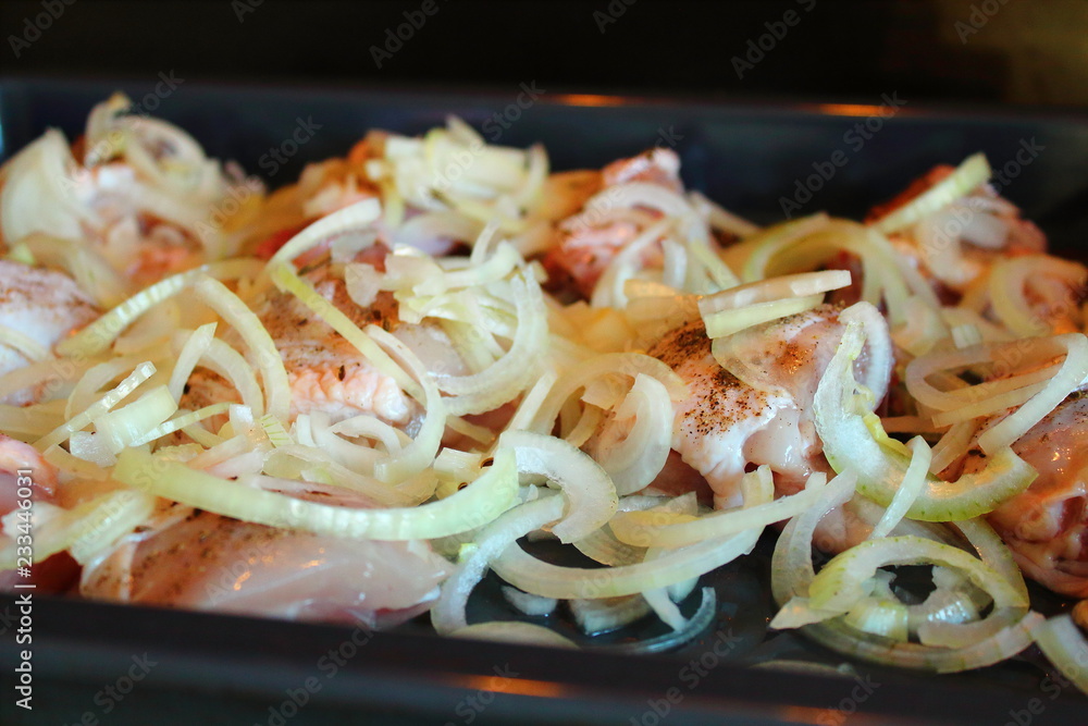 Sliced chicken with onions on a baking sheet. Close-up. Background. Sliced chicken with onions on a baking sheet. Close-up. Background.