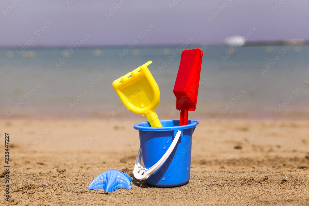 Toys on sandy beach in the foreground and blurred sea in the background. Toys on sandy beach in the foreground and blurred sea in the background.