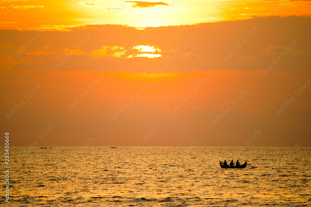 Silhouette of three fishermen in a boat against the setting sun