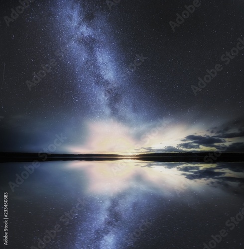 Dreamy surreal landscape with starry night sky and man silhouette