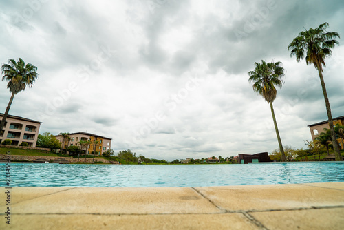 Fototapeta Naklejka Na Ścianę i Meble -  pool, buildings and palm trees against the sky