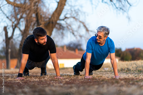 Senior father and son doing pushups outdoors
