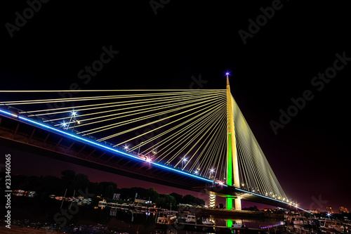 Belgrade, Serbia - 20 June, 2018: Side view of Ada bridge at night with reflection over Belgrade marina on Sava river