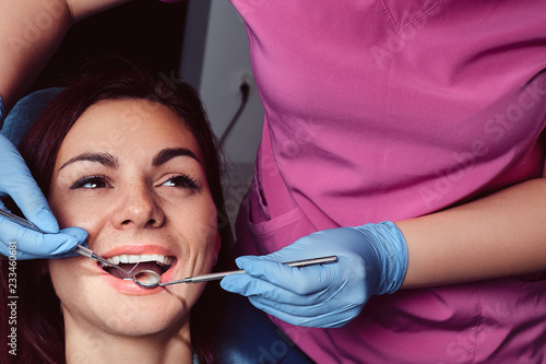 A young woman having examination while sitting in the dentist's chair with opened mouth.