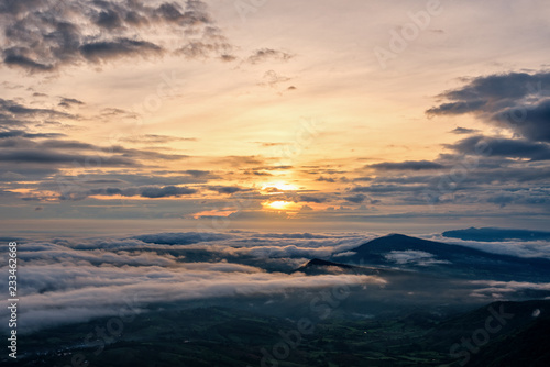 Beautiful nature landscape the sun is above the sea fog that covers the mountains and bright sky during sunrise in the winter at viewpoint of Phu Ruea National Park, Loei province, Thailand.