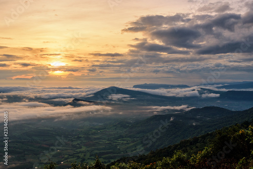 Beautiful nature landscape the sun is above the sea fog that covers the mountains and bright sky during sunrise in the winter at viewpoint of Phu Ruea National Park, Loei province, Thailand. © yongkiet