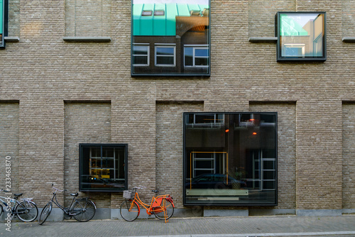 Frameless mirror square windows randomly set up on renovated old building exterior facade and bicycles park beside the building