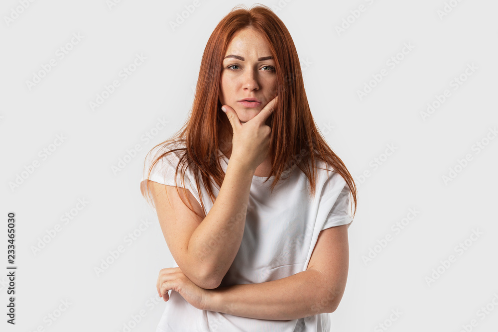 Young red-haired girl confidently looks into the camera. Isolated on gray background. Young red-haired girl confidently looks into the camera. Isolated on gray background.