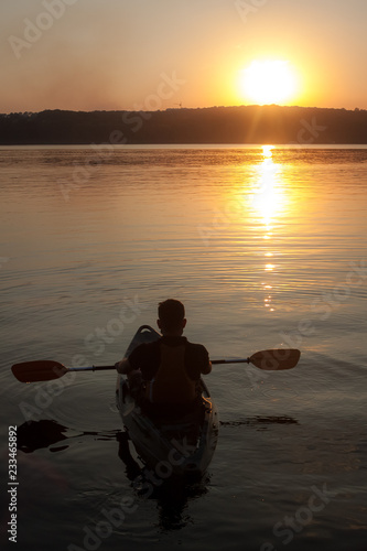 A man with paddle on kayak silhouette in sunset, from the top