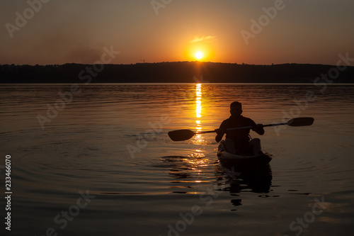A man paddling on kayak silhouette in sunset