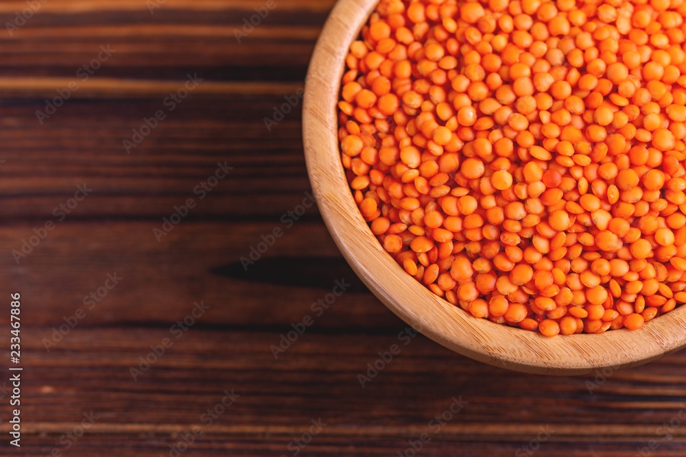 Raw red lentils in wooden bowl on rustic wooden background Raw red lentils in wooden bowl on rustic wooden background