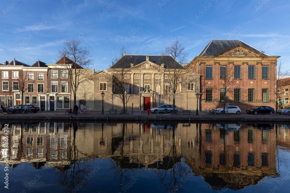 Autumn picturesque view on an old part of the city Leiden with classic facades against a blue sky with the scene doubled as a reflection in the water of the passing canal