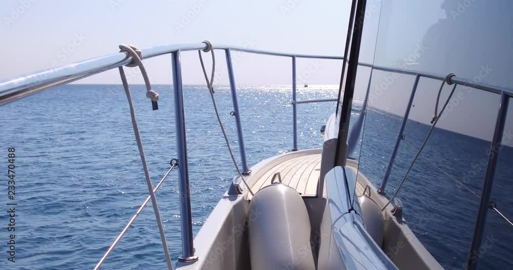 On board side view of a yacht navigating on blue sea vawes. Luxury yacht floats on blue sea waves. Sailing in the wind through the waves On board side view of a yacht navigating on blue sea vawes. Luxury yacht floats on blue sea waves. Sailing in the wind through the waves